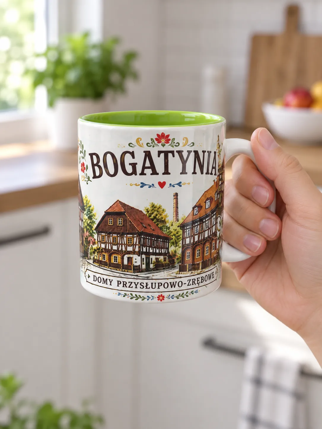 Kubek ceramiczny z zielonym wnętrzem i pełnokolorowym nadrukiem pamiątkowym, trzymany w dłoni na tle kuchni.
